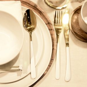 From above of porcelain dishware with napkin and wooden stand on served table during celebration