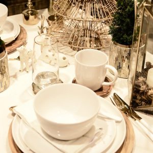 From above of served table with set of dishware near decorative deer statuettes and small Christmas tree during festive event in restaurant